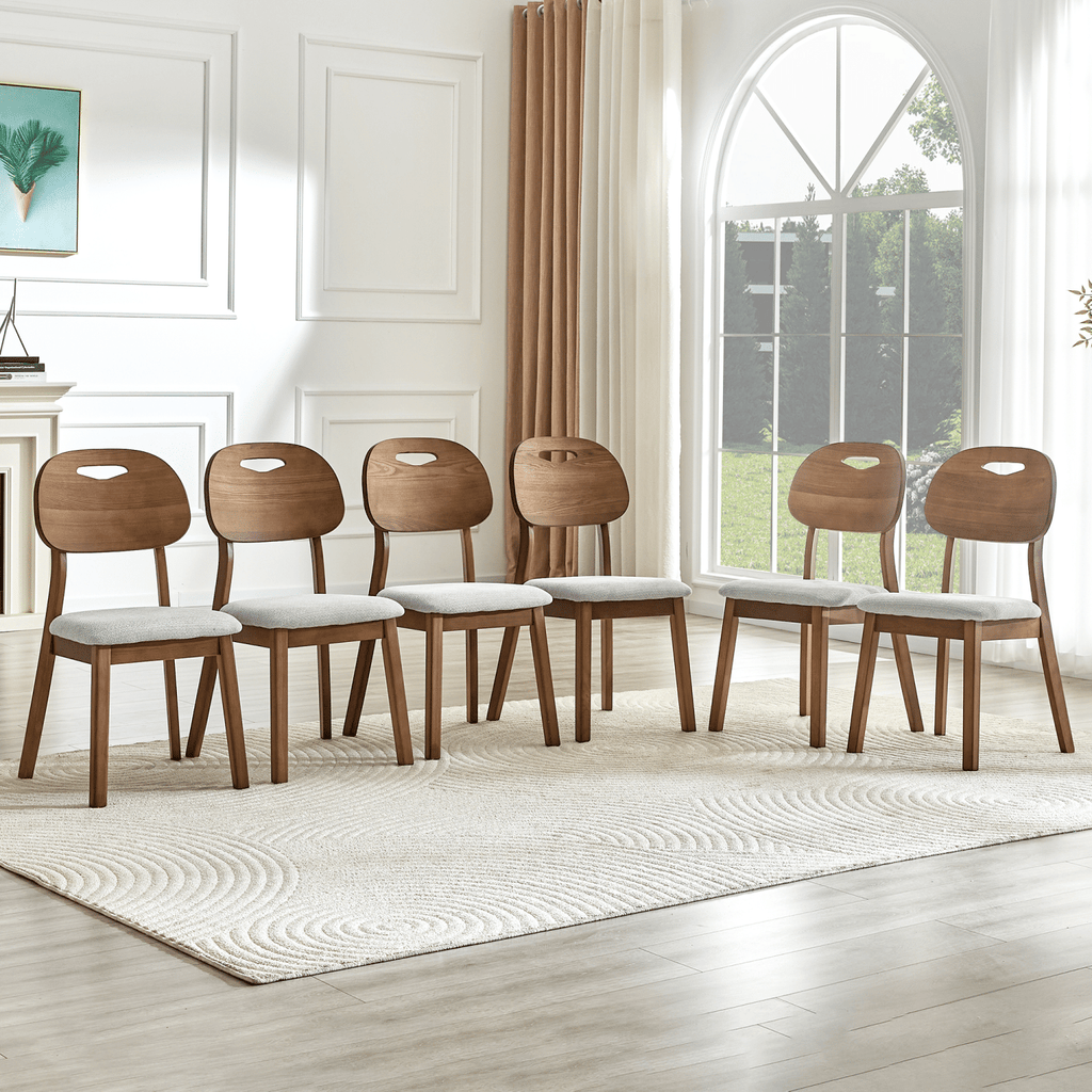 2 walnut colored solid wood dining chairs, with gray breathable fabric wrapped cushions and hollowed out backrests, suitable for home dining.